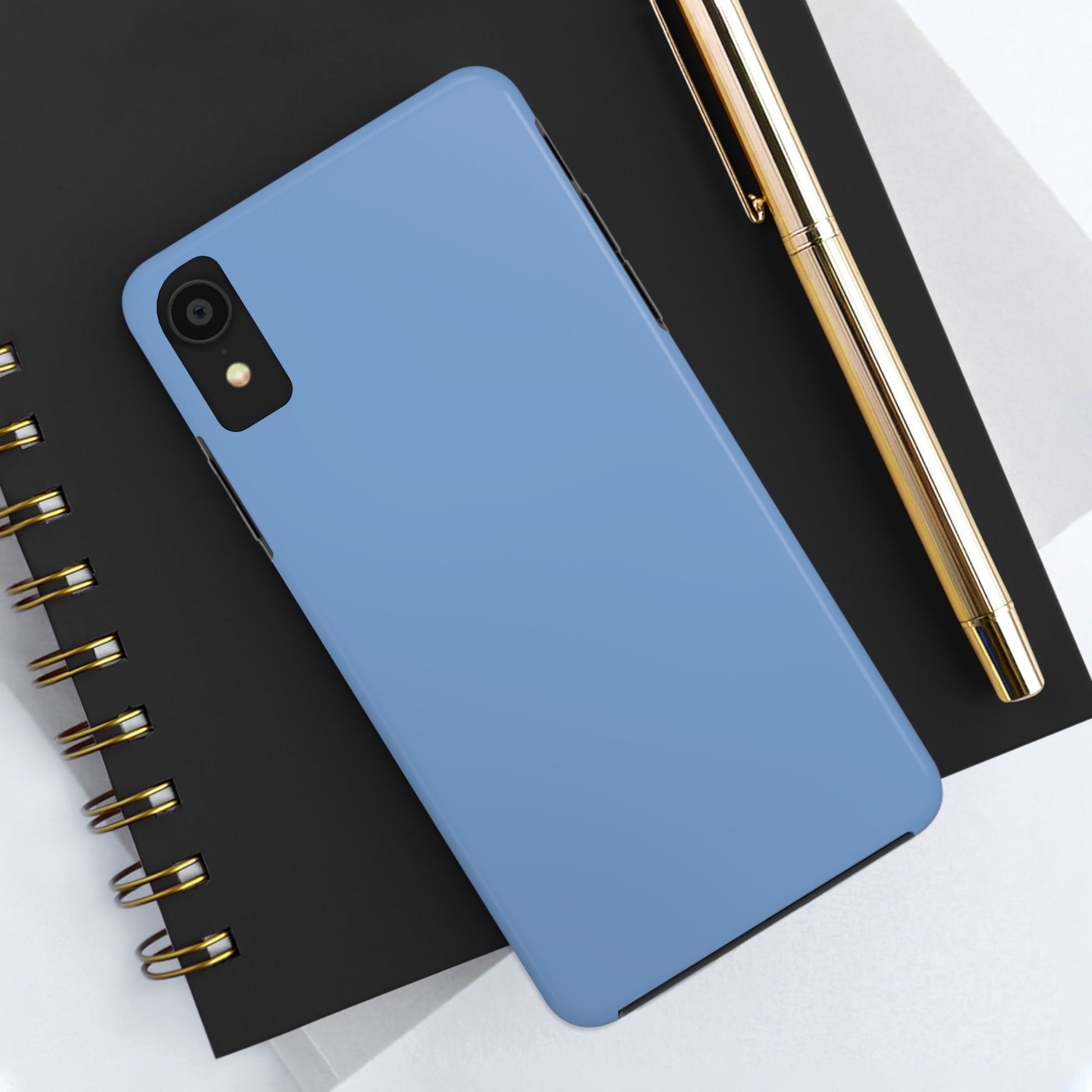 Blue phone case on a black notebook with a gold pen
