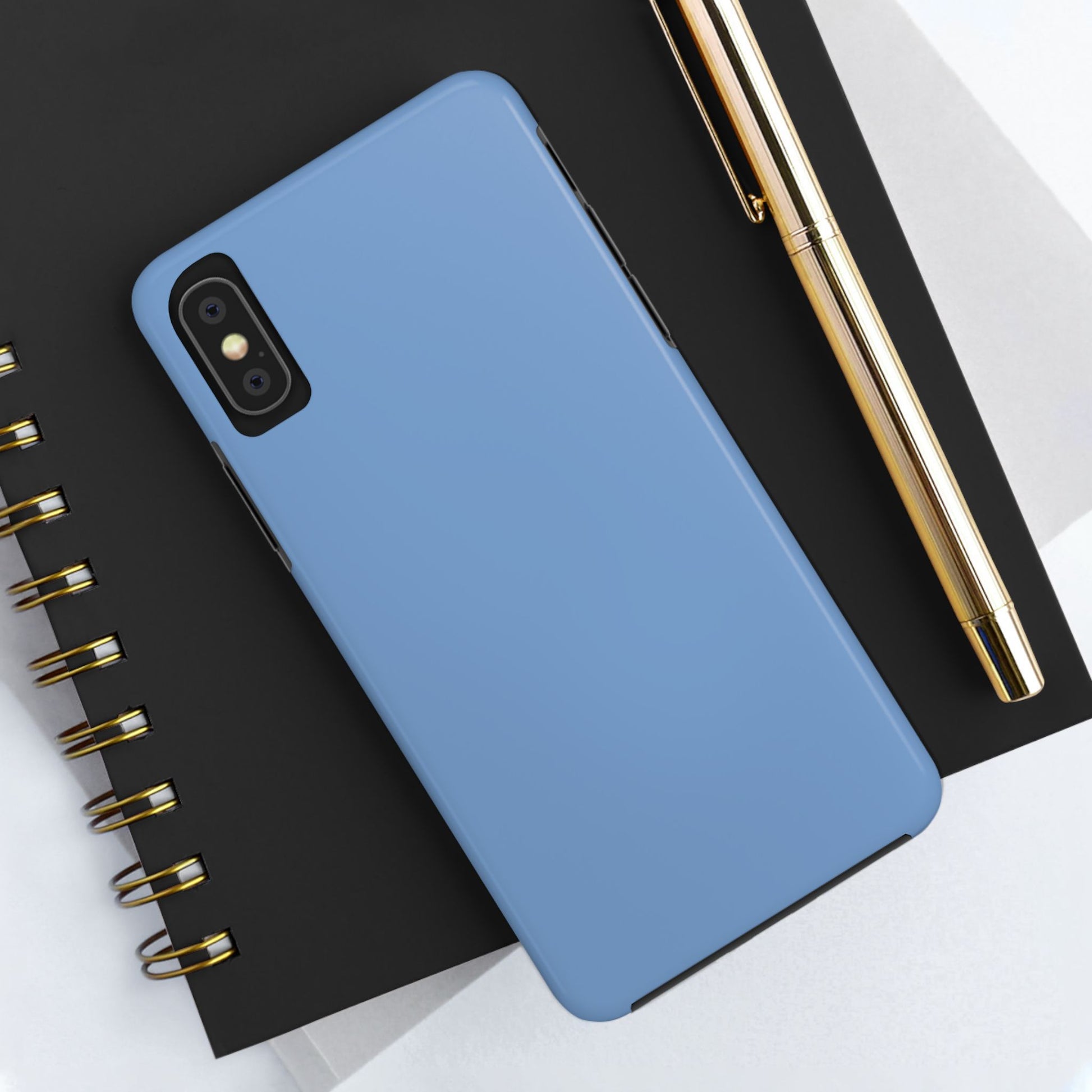 Blue phone case on a black notebook with a gold pen