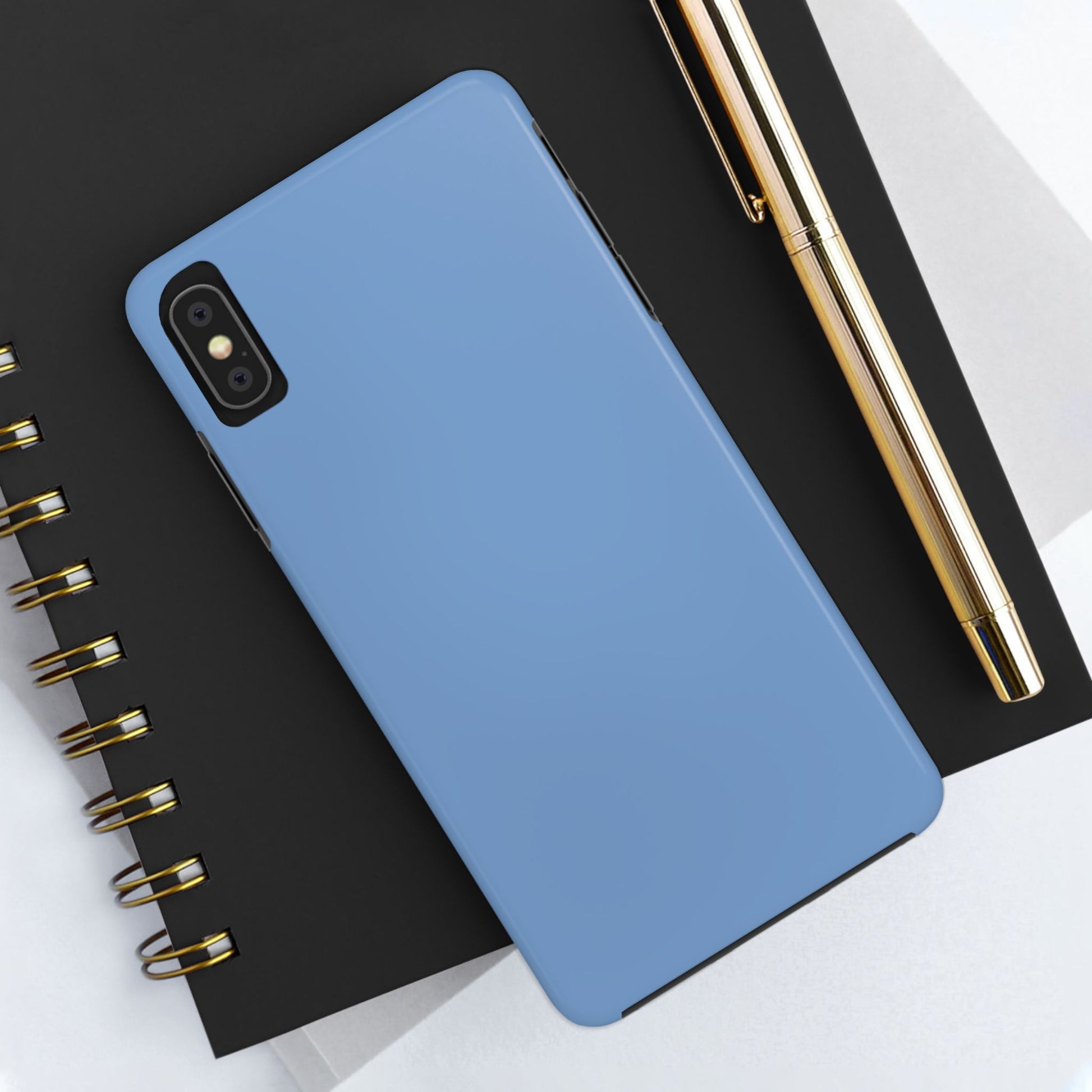 Blue phone case on a black notebook with a gold pen